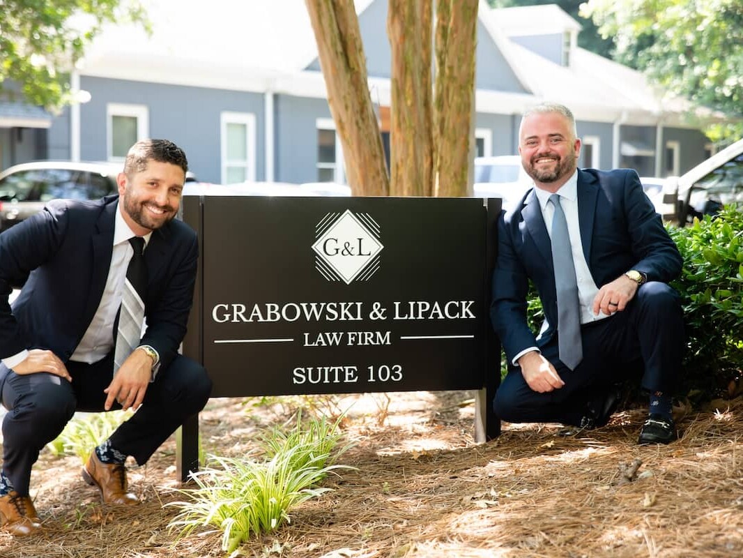 Grabowski and Lipack sign with attorneys posed next to it