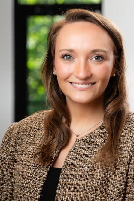 Smiling woman with brown hair and brown suit