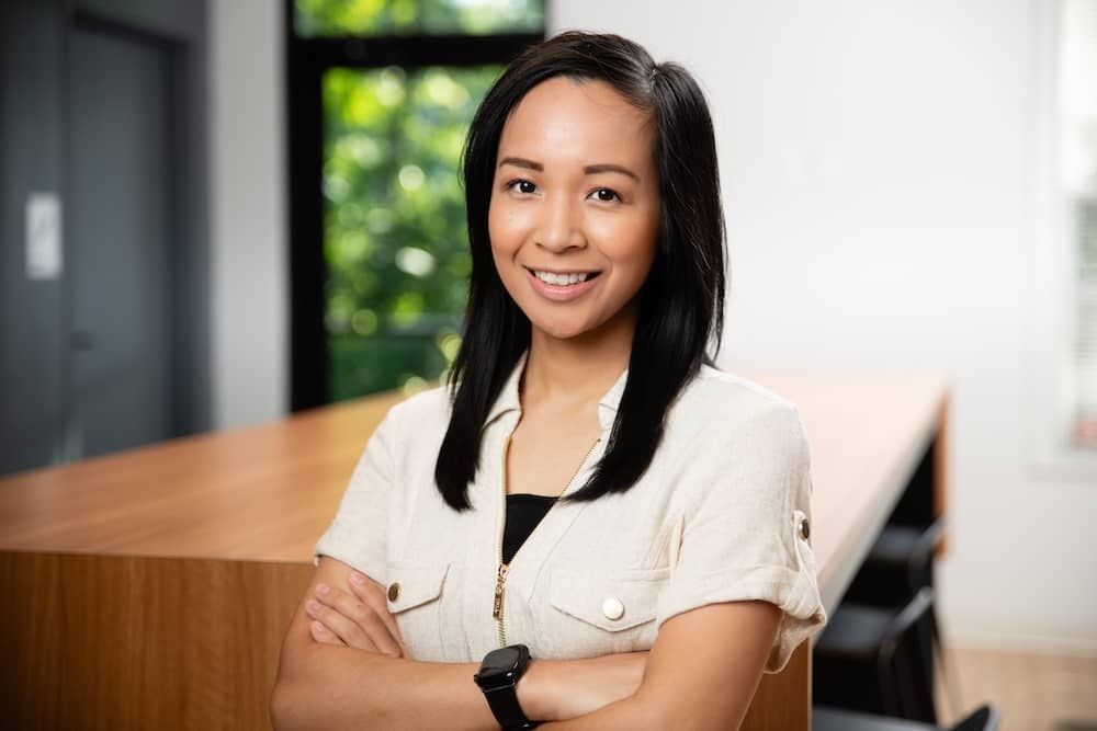 Smiling young woman with dark hair and tan shirt