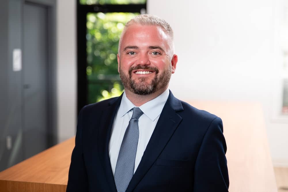 Smiling gray haired man with short beard wearing suit with blue tie