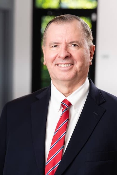 Smiling older man in suit and red striped tie