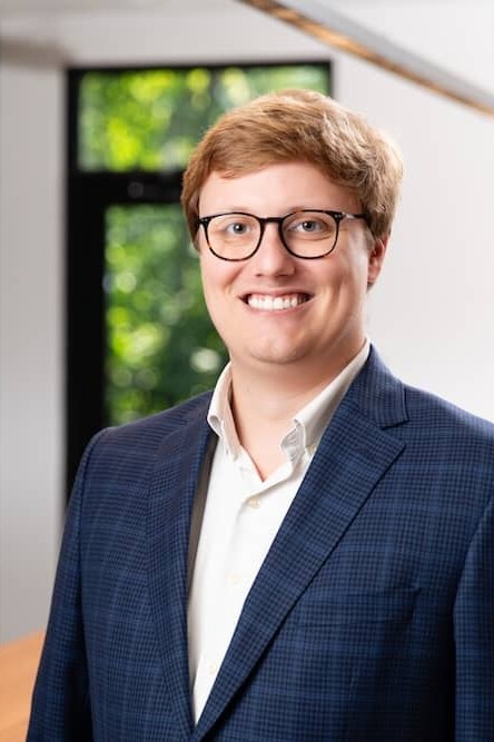 Smiling red haired man in blue suit wearing glasses