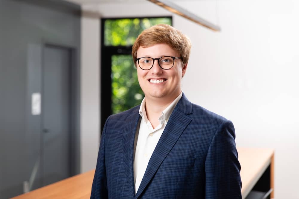 Smiling red haired man in blue suit wearing glasses